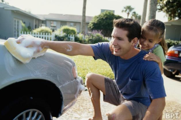 Man washing car with kid on his back