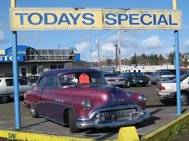 purple car in front of dilapidated used car lot