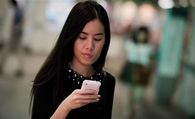asian girl holding smartphone and looking at it