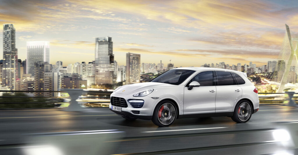 Porsche Cayenne Turbo S driving on a bridge with a city in the background