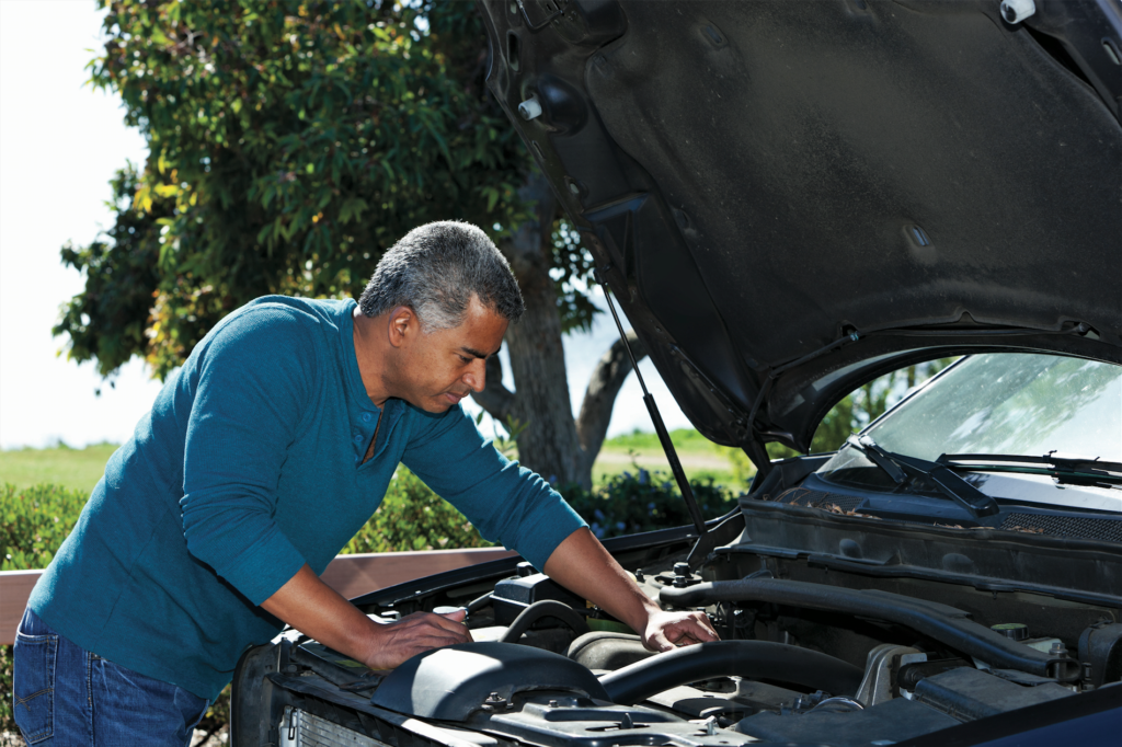 grey haired latino man fixing car
