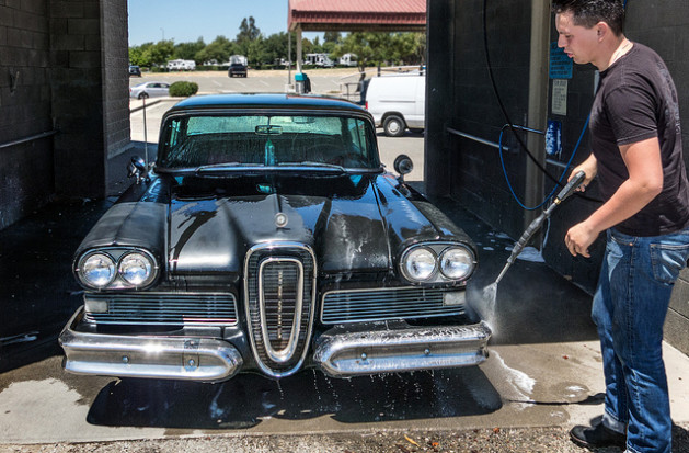 man washing classic car