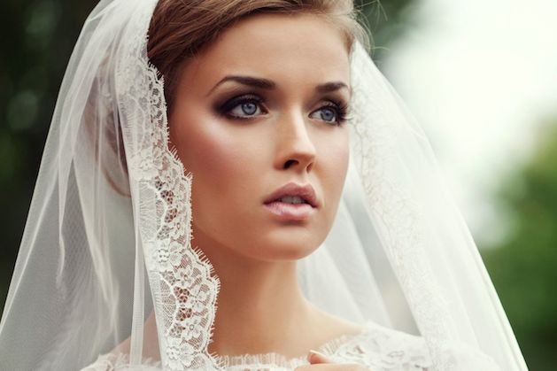 bride in gown and veil wearing makeup