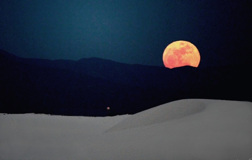 red moon over sand dunes