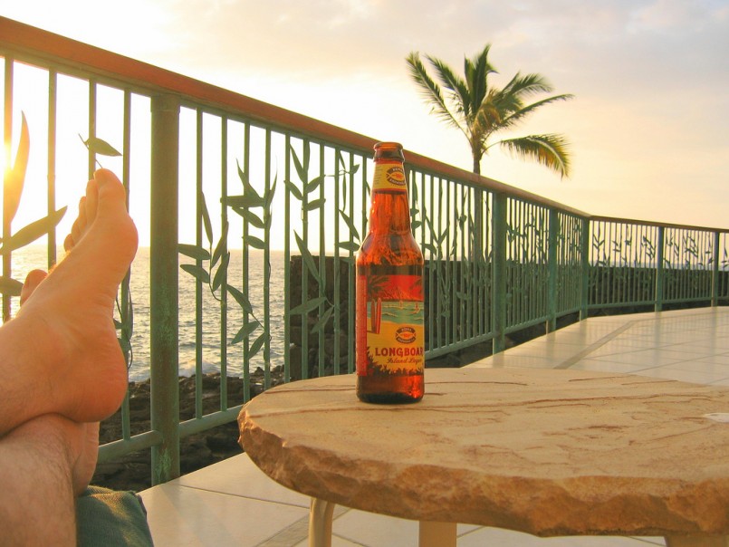 beer on porch by palm tree and ocean