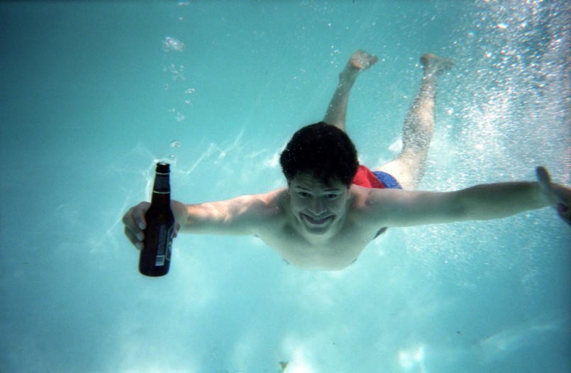man underwater holding a beer