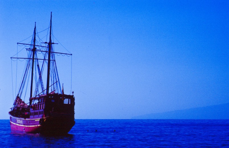 Pirate ship with pink sunset on blue ocean