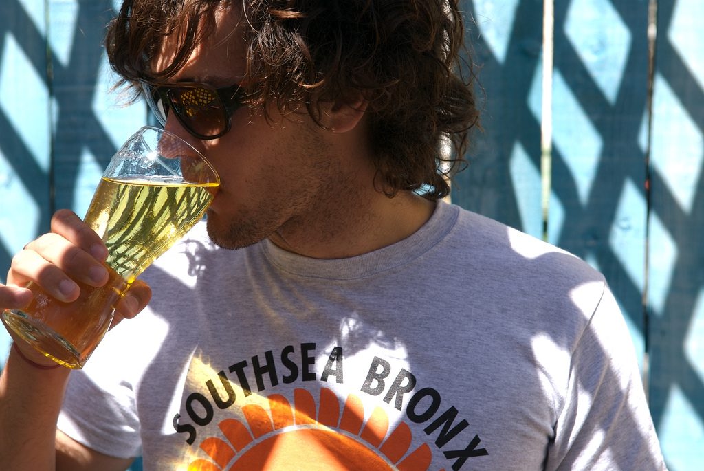 brown haired man with sunglasses drinking beer