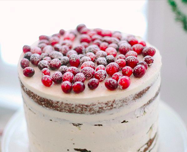 naked white wedding cake topped with cranberries
