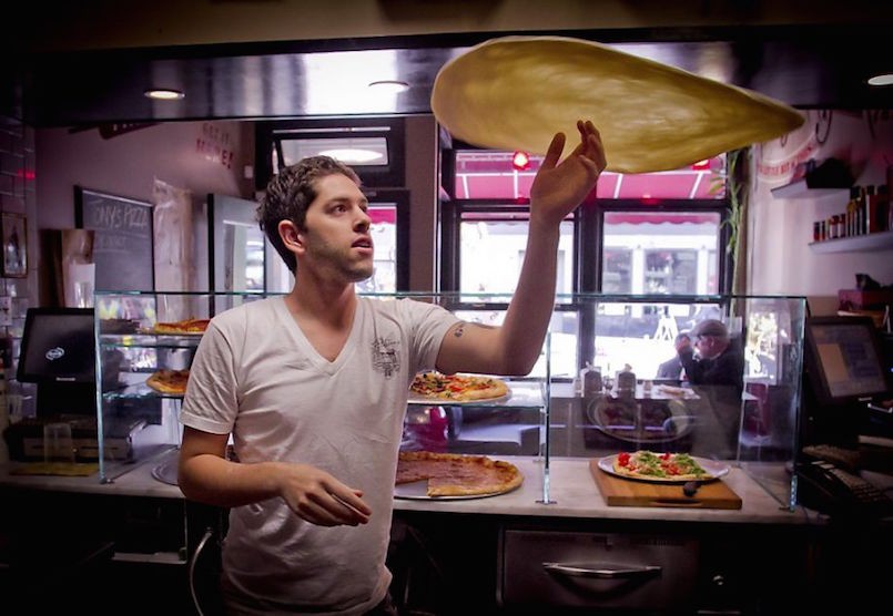 young man tossing pizza dough