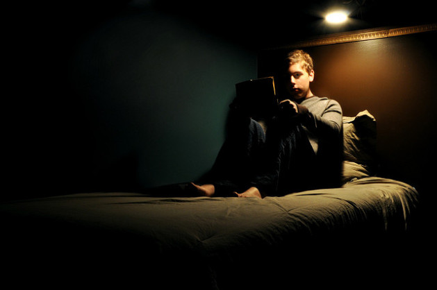 young boy reading in dark bed