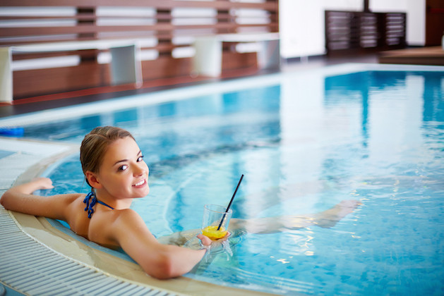 Young woman sitting with lemonade in swimming pool