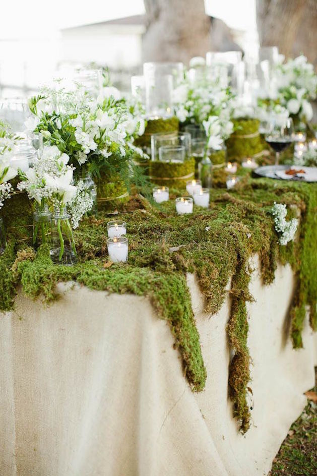 linen table cloth covered in moss and candles