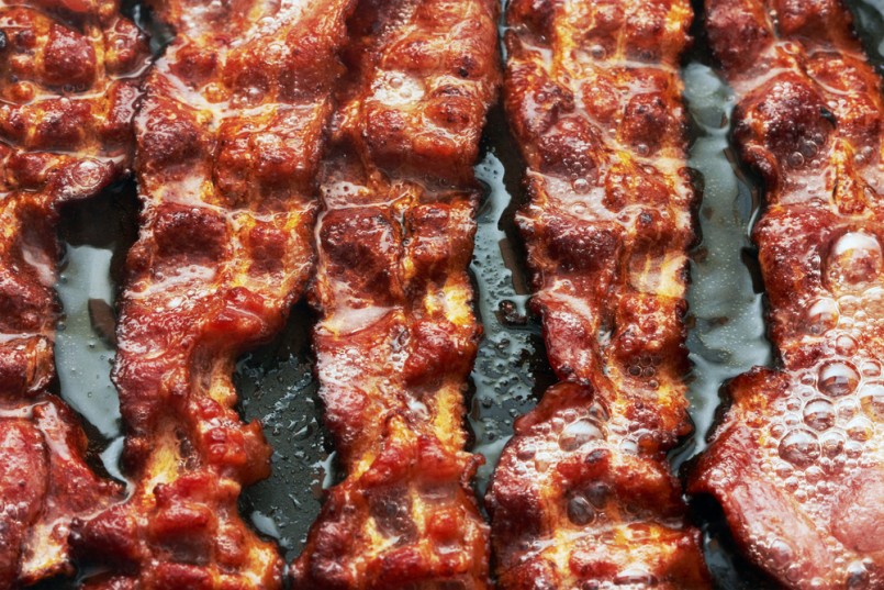 Bacon slice being cooked in frying pan