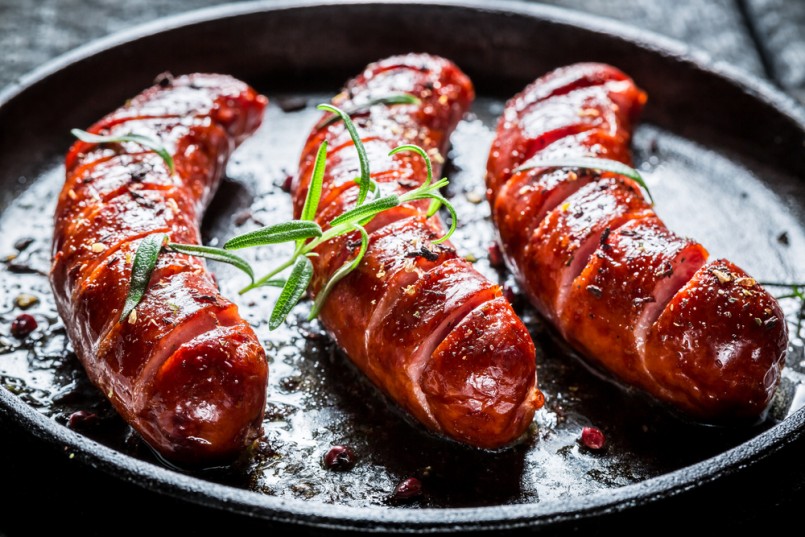 Grilled sausage with fresh rosemary on hot barbecue dish