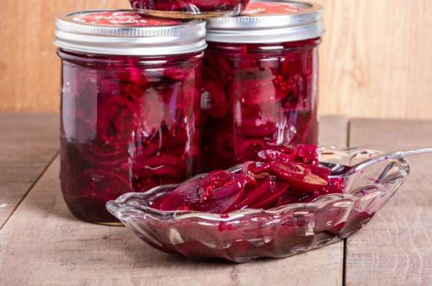 Red pickled beets in mason jars being served in a bowl