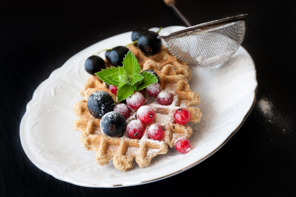 Sweet Waffles with black and red currants on a black background