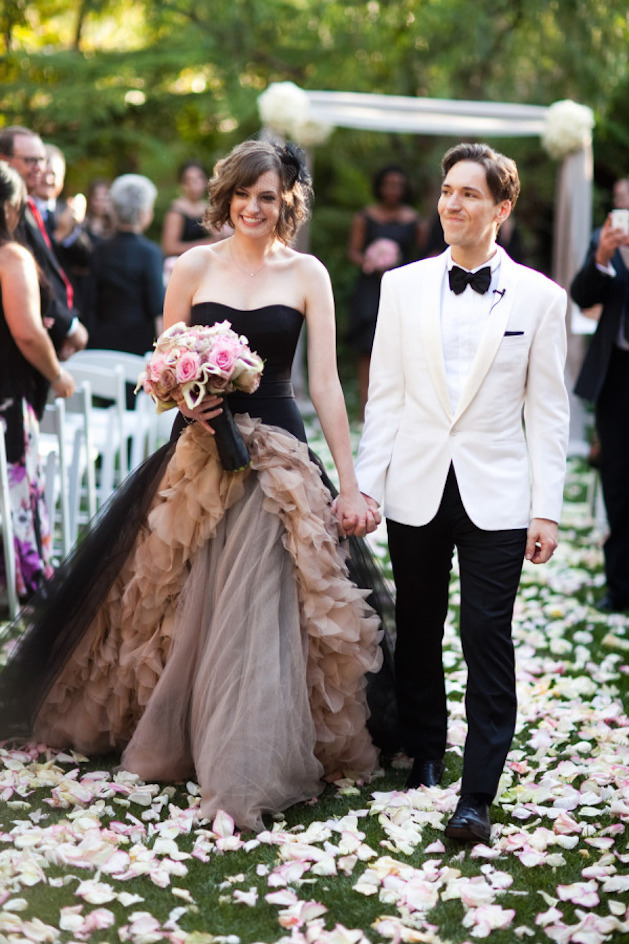 bride in chocolate brown dress and groom in black and white tuxedo walking down the aisle