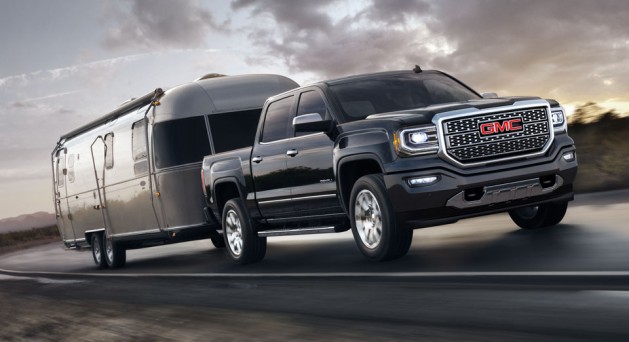 2016 Sierra 1500 Denali in black towing trailer on the road