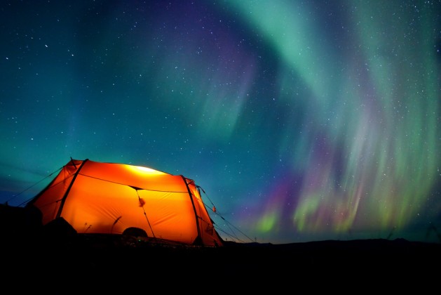 Northern lights over a illuminated tent in Lapland