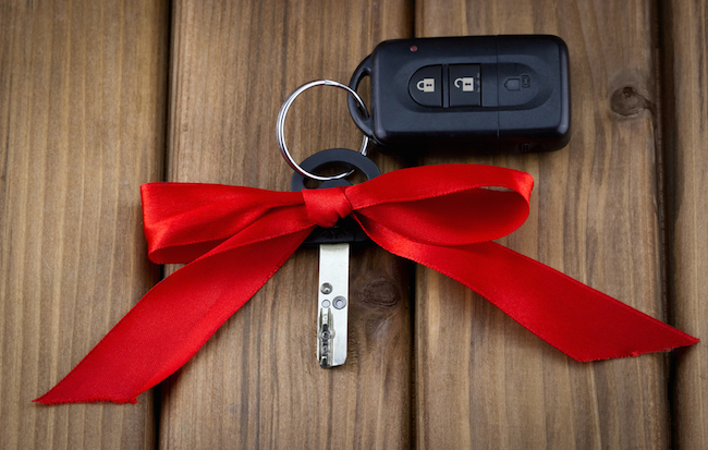 Close-up view of car keys with red bow as present on wooden background