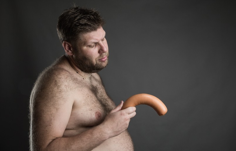 Sad man looks at the sausage in his hand