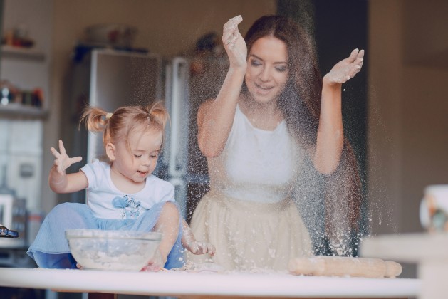 young beautiful mother teaches daughter prepare dough in the kitchen