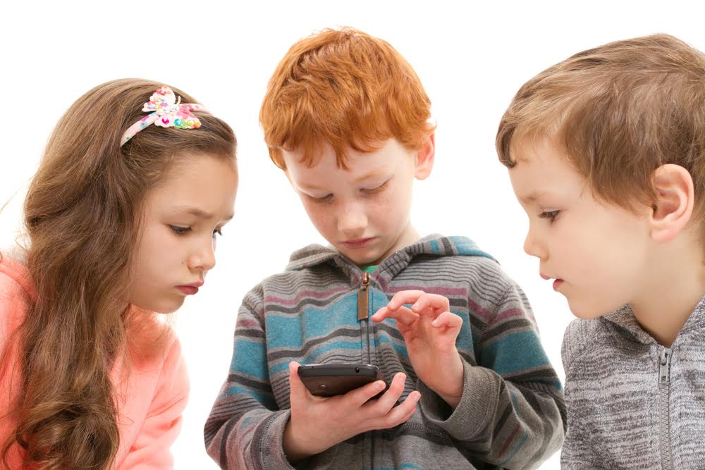 Three children watching child using smartphone. Isolated on white.