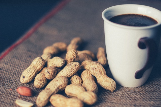 peanuts next to a white cup of coffee