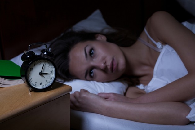 Woman with insomnia lying in bed with open eyes