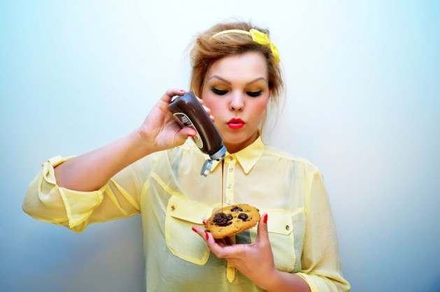Young Woman Pouring Chocolate Sauce Over Chocolate Chip Cookie