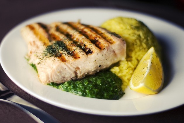 grilled swordfish on white plate with lemon wedge