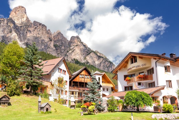 A classical view of the dolomites. Typical houses under the shadow of the Saslong Mountain in Corvara during a sunny day