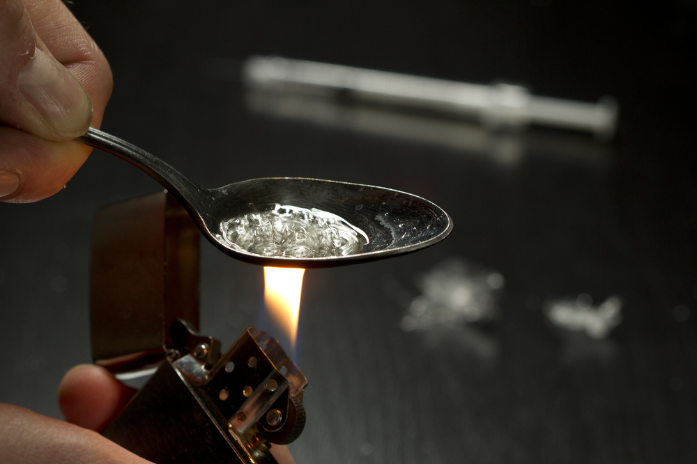 Close up of person cooking heroin using lighter