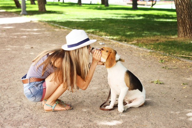 Cute girl kissing her beagle dog in nature outdoors. Lovely shot