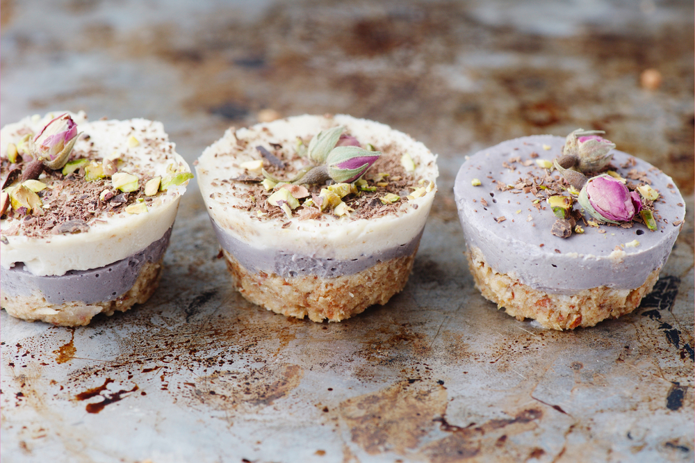 Vegan mini cheesecakes with blueberry and white chocolate layer with adding of cashews, cacao butter and coconut milk, and base made of almonds, shredded coconut and medjool dates (selective focus)