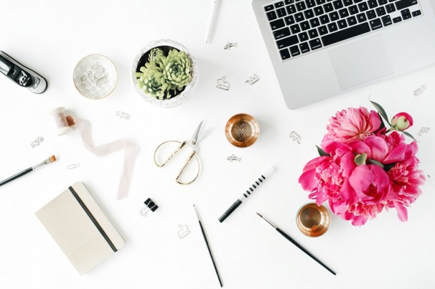 Flat lay, top view office table desk. Workplace with laptop, succulent, peonies, golden scissors, spool with beige ribbon, pencils and diary.