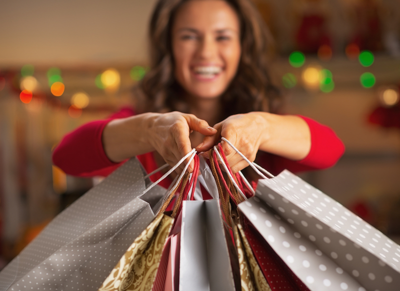 Closeup on christmas shopping bags in hand of smiling young woman