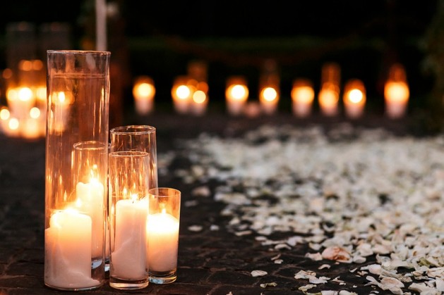 Fairytale romantic wedding aisle with white candles and petals in the evening