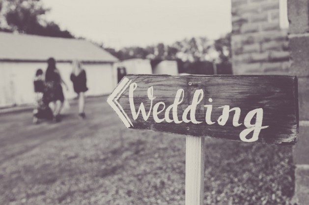 Black and white vintage country wedding wedding sign with guests blurred in background.