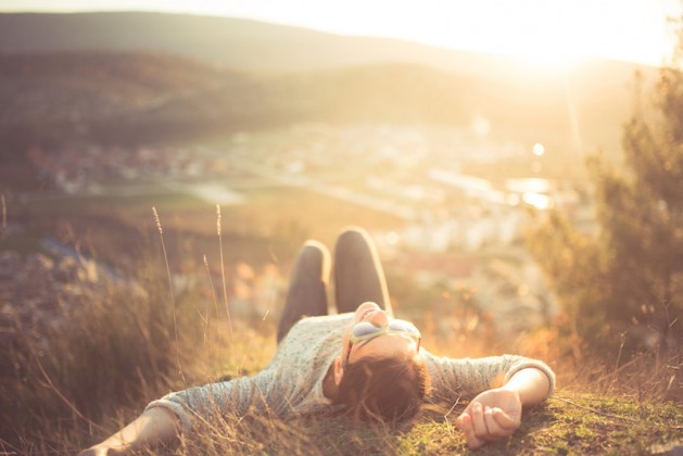 carefree-happy-woman-lying-on-green-grass-meadow-on-top-of-mountain-edge-cliff-enjoying-sun-on-her-face-enjoying-nature-sunset-freedom-enjoyment-relaxing-in-mountains-at-sunrise-sunshine-daydreaming