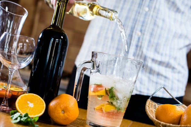 Man pouring white wine into a jar, making sangria for home party, home kitchen interior. Homemade food and drinks