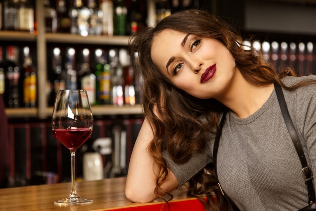me-and-my-dreams-portrait-of-a-gorgeous-red-lipped-young-woman-looking-away-dreamily-smiling-while-having-a-glass-of-wine-at-the-bar-single-woman-millennial