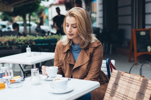 beautiful-blond-woman-sitting-alone-in-cafeteria-and-drinking-coffee