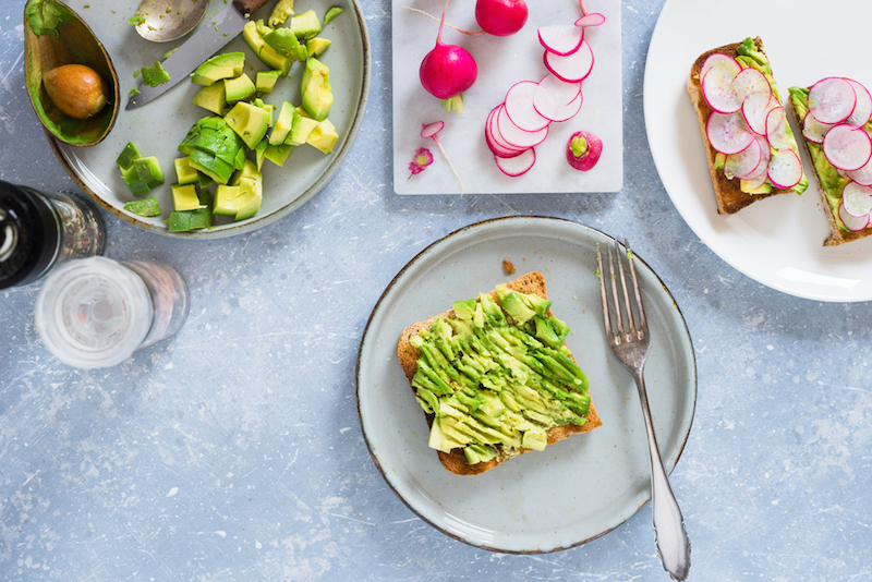 Smashed avocado on whole grain toast to make avocado and radish sandwiches