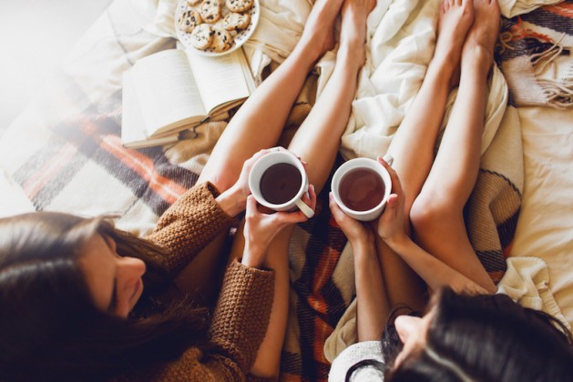 soft-photo-of-two-sisters-on-the-bed-with-old-books-and-cup-of-tea-in-hands-wearing-cozy-sweater-top-view-point-two-best-friends-enjoying-morning