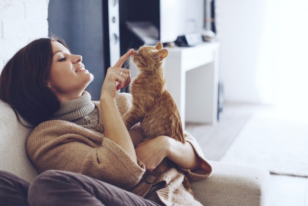 young-woman-wearing-warm-sweater-is-resting-with-a-cat-on-the-armchair-at-home-one-autumn-day