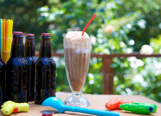 Root beer float outdoors with ice cream scoop, straws, squirt guns and bottles