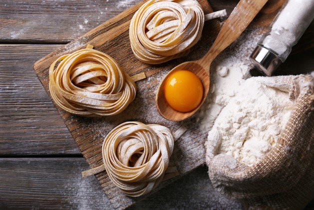 Raw homemade pasta and ingredients for pasta on wooden background