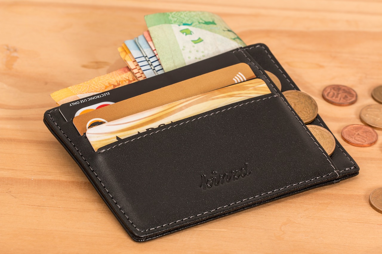 Wallet holding credit cards with coins coming out